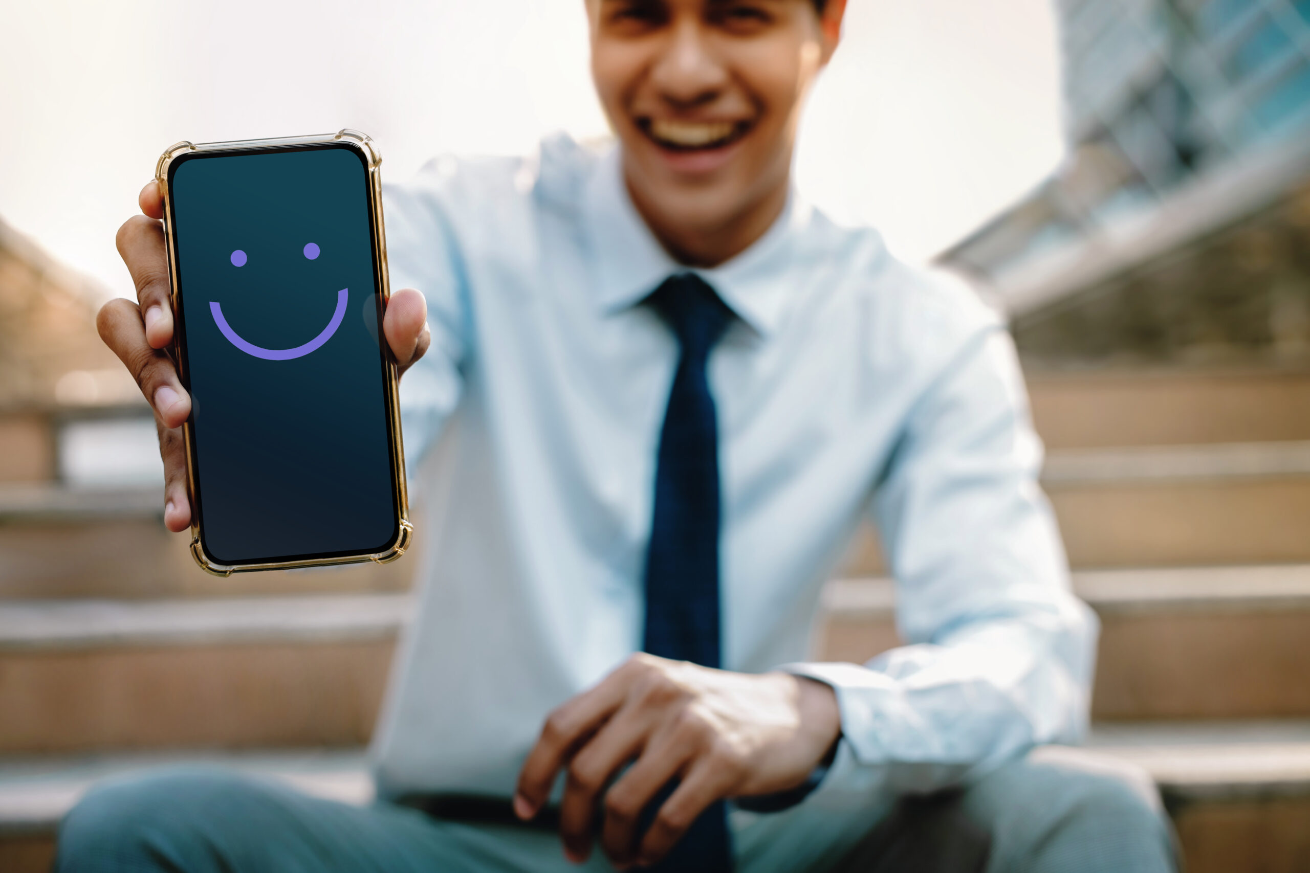 Young happy businessman showing his phone