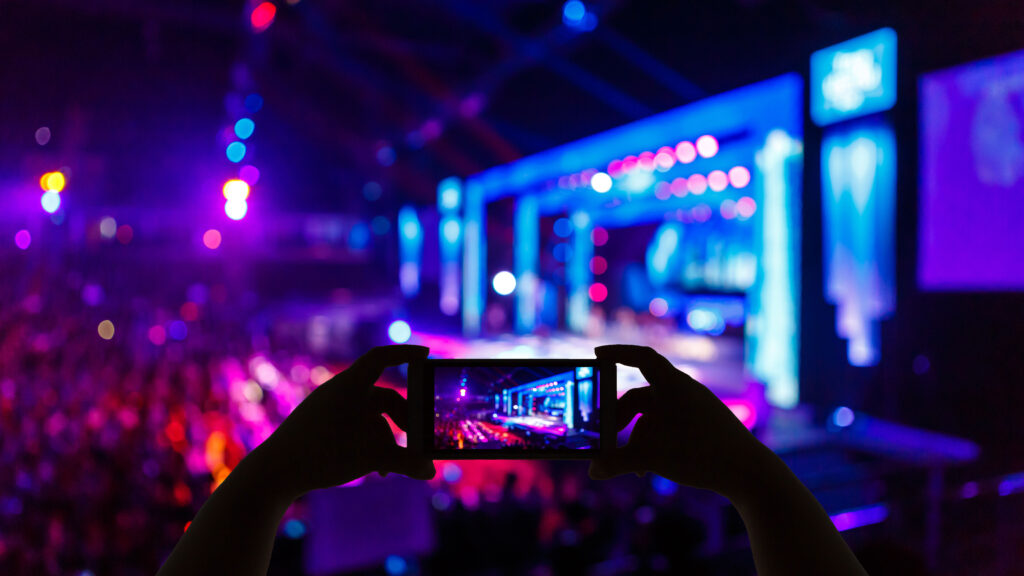 Person takes a photo or video using their mobile device, during a music concert