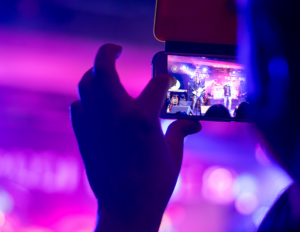 Person takes a photo using their mobile device, during a music concert